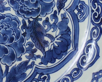 A close-up of a Kangxi plate decorated with blue and white peonies, showing the delicate decoration and glaze
