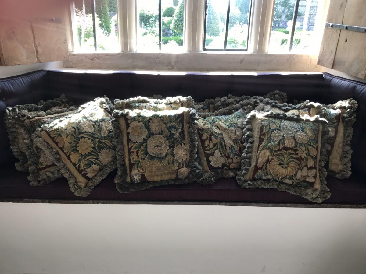 A rare set of eight, mid-17th century, verdure tapestry cushions with custom-made passmenterie