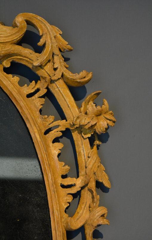  A George III carved oval ochre painted pine mirror