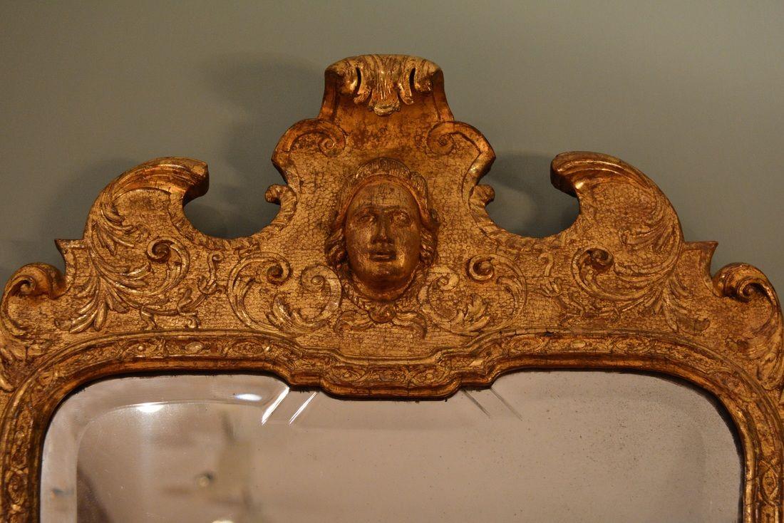  A finely carved gilt gesso mirror having candle arms to the base