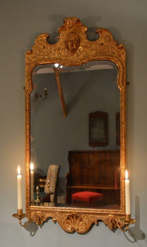  A finely carved gilt gesso mirror having candle arms to the base