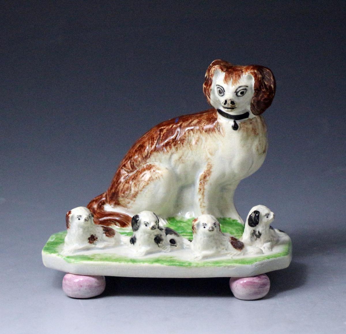 Antique English or Scottish pottery figure of a spaniel with four pups on bases with ball feet