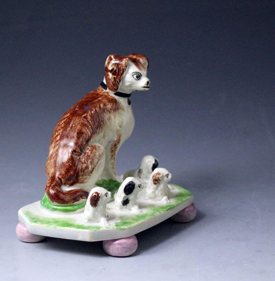 Antique English or Scottish pottery figure of a spaniel with four pups on bases with ball feet