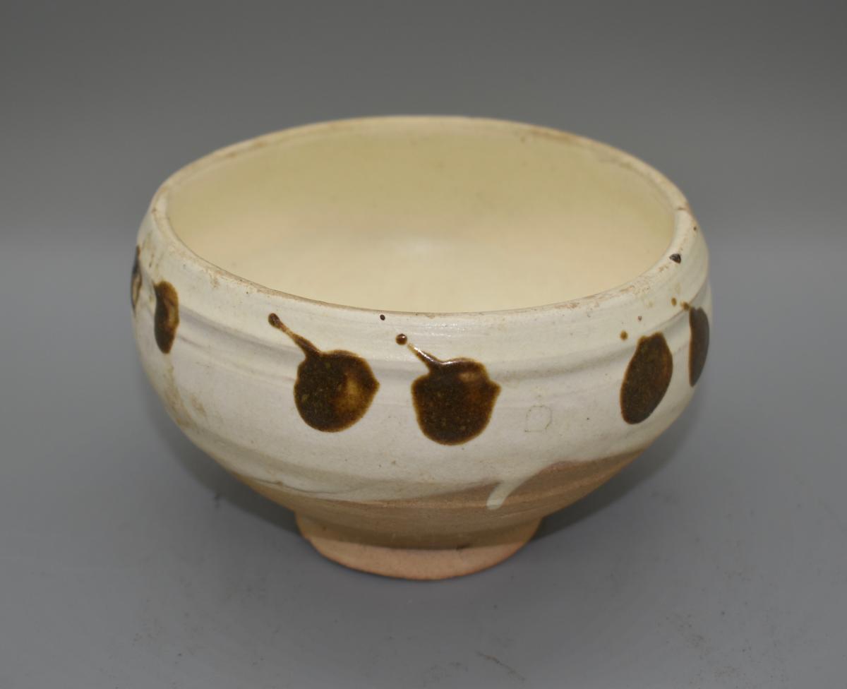 A white glazed bowl with russet-brown splashes