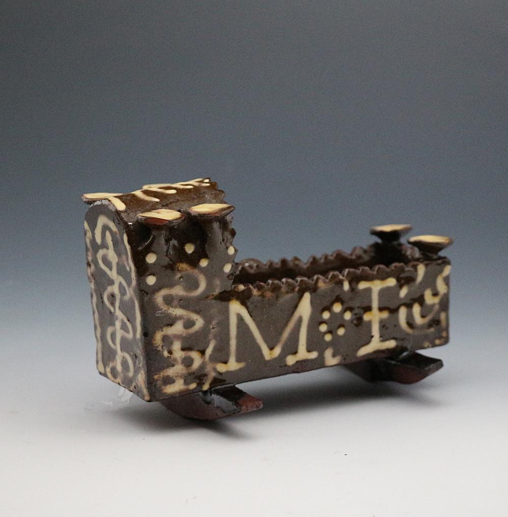 Antique English earthenware cradle dated 1847 and with the initials M:I in slip decoration.