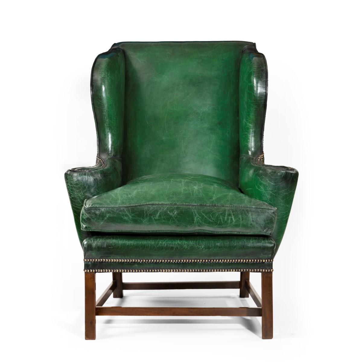 A George III style green leather wing arm chair