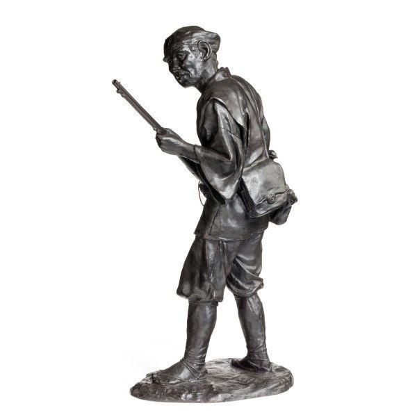 A Meiji period bronze of a huntsman carrying a gun