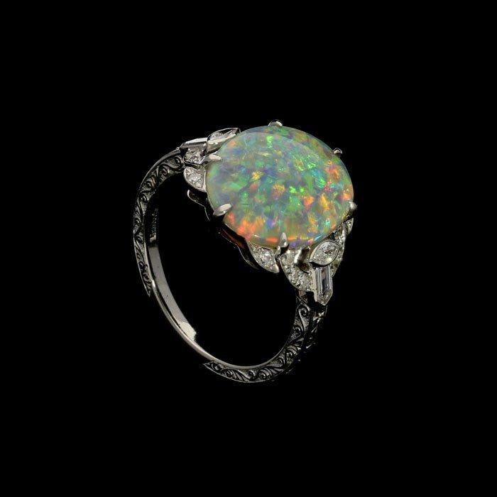 A beautiful white opal ring set in platinum with diamond shoulders and hand engraved details