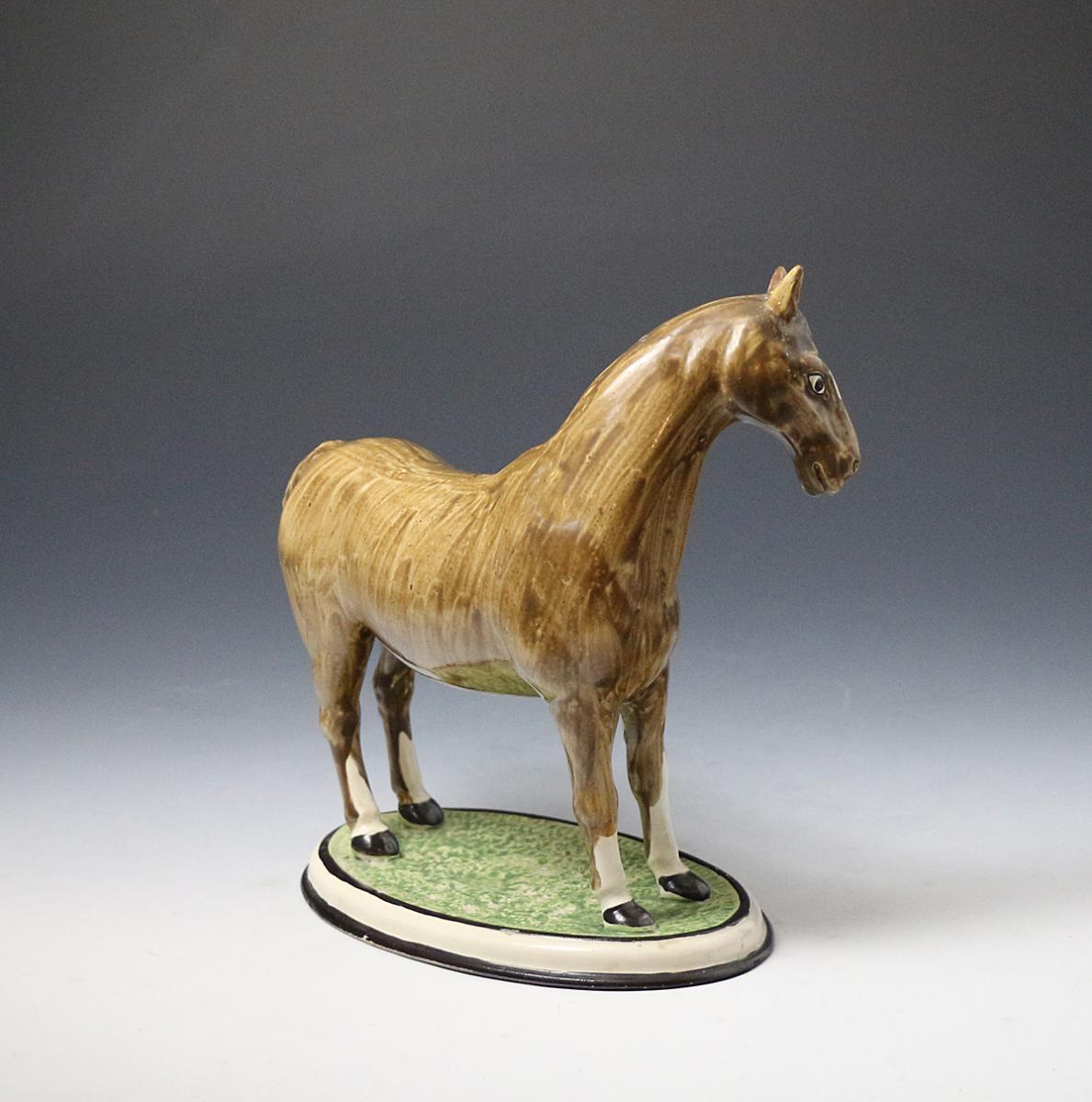 Pottery figure of a horse standing on an oval shaped base made England circa 1800