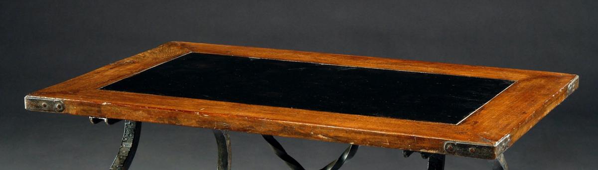 An 18th century, oak top with slate inset united with a contemporary, Spanish influenced low iron base