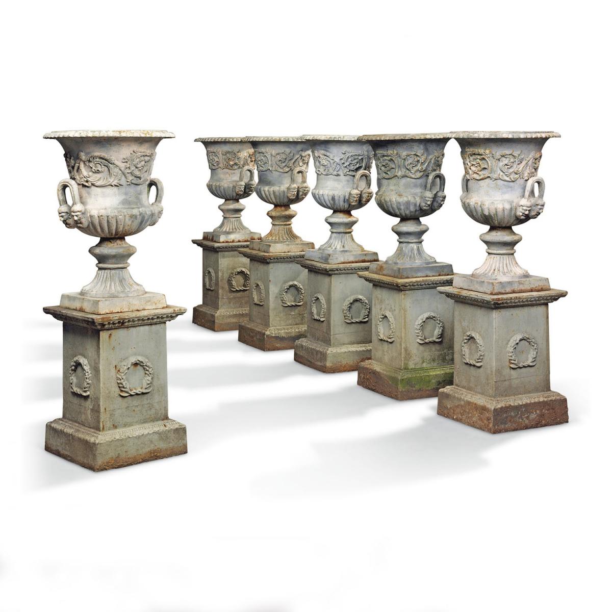 ten cast iron urns on pedestals