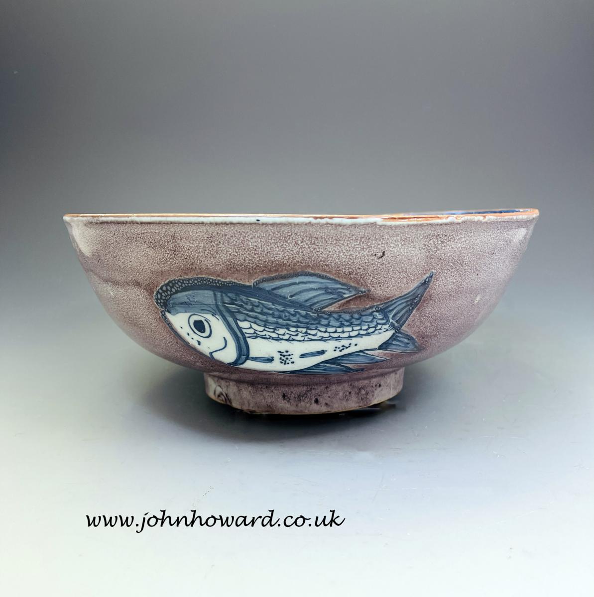 English delftware pottery bowl with manganese ground decorated with three blue fish 18th century