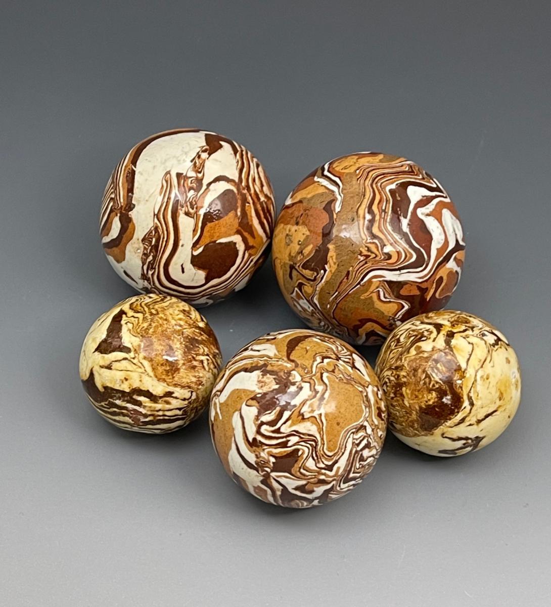 A collection of five English pottery slipware agateware balls late 18th century