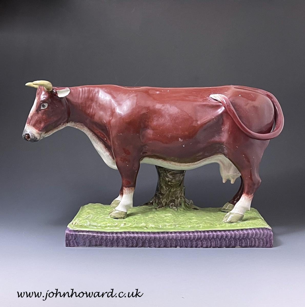 Large scale pottery pearlware figure of a cow standing on a base Staffordshire England early 19th century