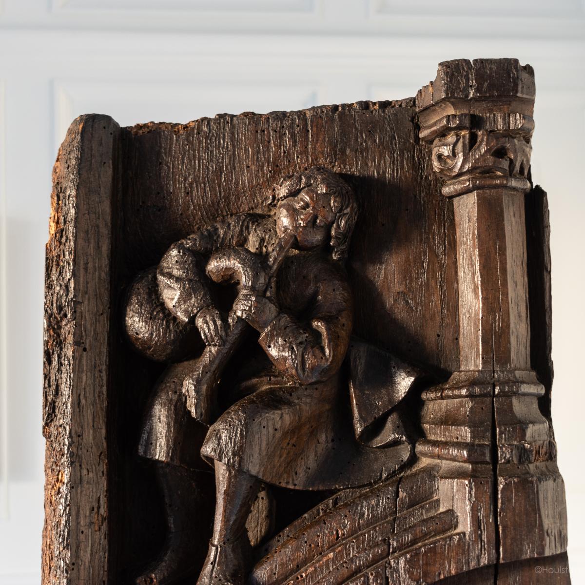A rare mid-15th century carved oak panel of a musician, English, circa 1450