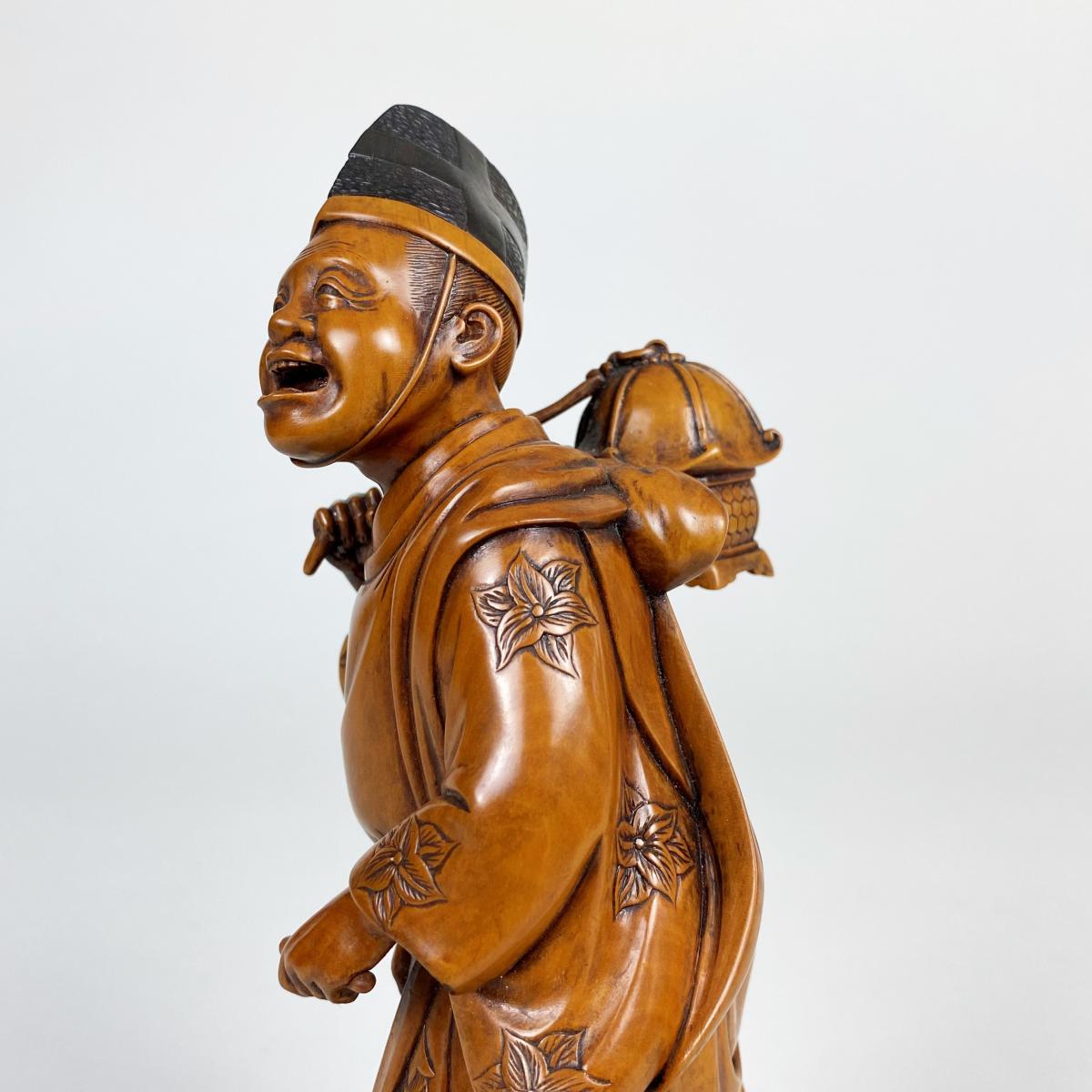 A charming wood carved Okimono depicting a man carrying a lantern