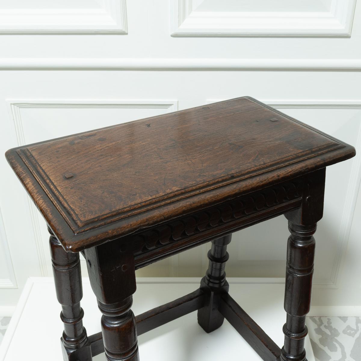 A dark oak antique four legged stool - detail of the top