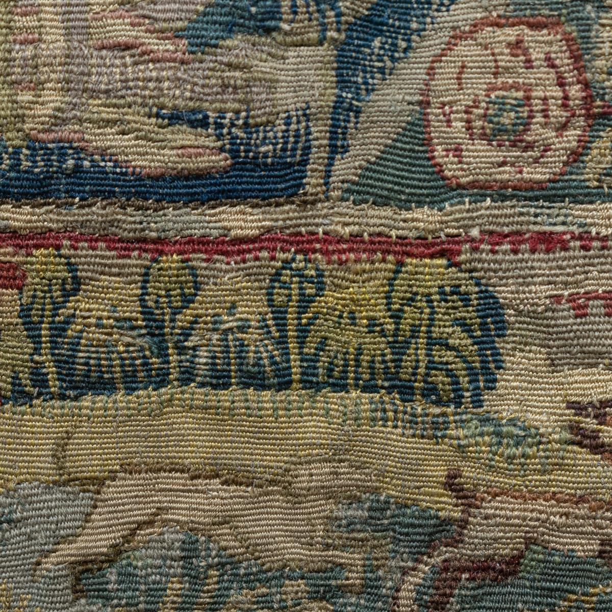 An antique tapestry cushion cover in a frame