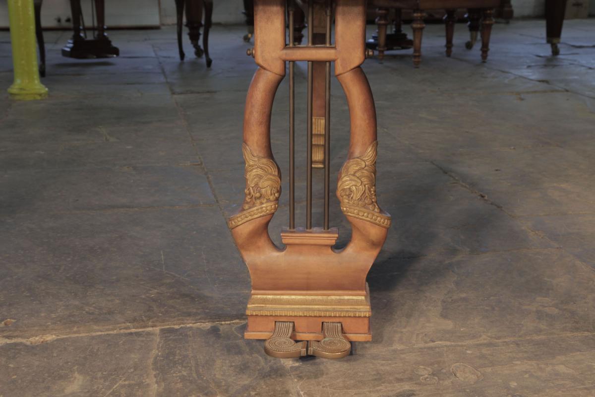The two-pedal piano lyre is carved with berries and leaves, accented in gilt. Piano pedals are shaped as two spirals with studded decoration. 