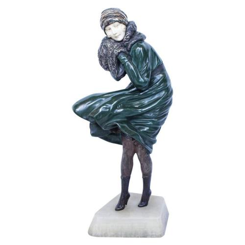 "The Squall", an early 20th Century, Art Deco, cold painted bronze and ivory figurine of a young woman in a long coat, battling against strong winds. Hand finished surface details and enamel colours, raised on an onyx plinth. Signed 'Chiparus'.