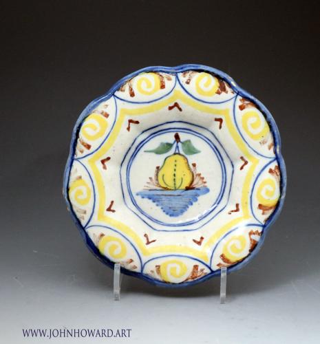 Antique delftware lobed dish polychrome coloured with image of a pear in the central panel