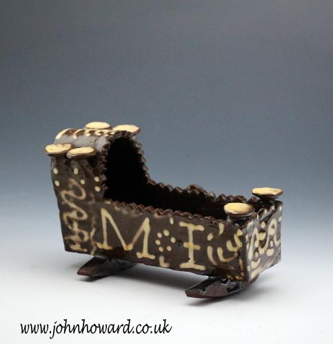 Antique English earthenware cradle dated 1847 and with the initials M:I in slip decoration.