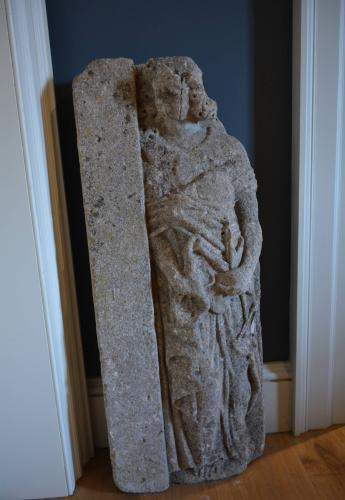 A stone carving of a figure holding the scales of justice  English Circa 1500