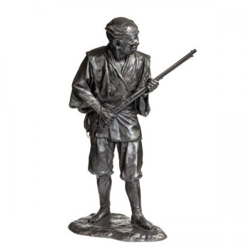 A Meiji period bronze of a huntsman carrying a gun