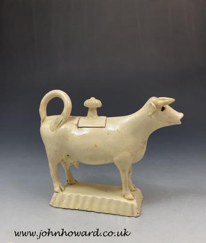 Early Staffordshire creamware bodied pottery cow creamer on a shaped canted base c1760