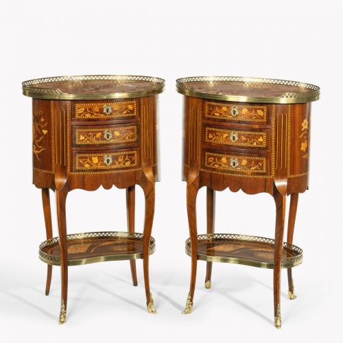 A pair of French rosewood oval marquetry bedside tables with marble tops