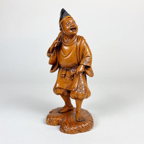 A charming wood carved Okimono depicting a man carrying a lantern
