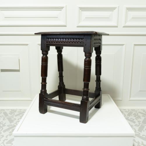 A dark oak antique four legged stool