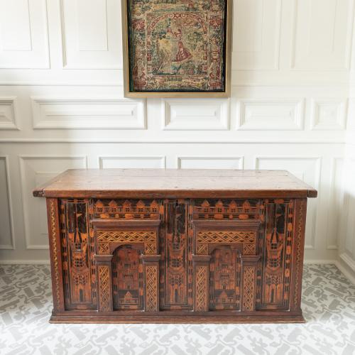 A large antique oak chest with architectural details and inlay in a room setting