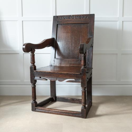 A rare Charles II commemorative joined oak panel-back open armchair, initialled and dated