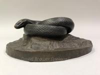 American bronze sculpture of a snake coiled upon a rock