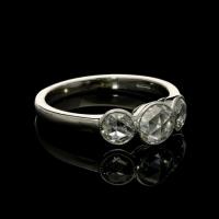 A pretty three stone diamond ring set with 1.21cts of rose cut diamonds in milegrained platinum