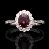 A classic oval ruby and round brilliant diamond cluster ring set in platinum