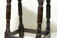 A dark oak antique four legged stool - detail of the legs
